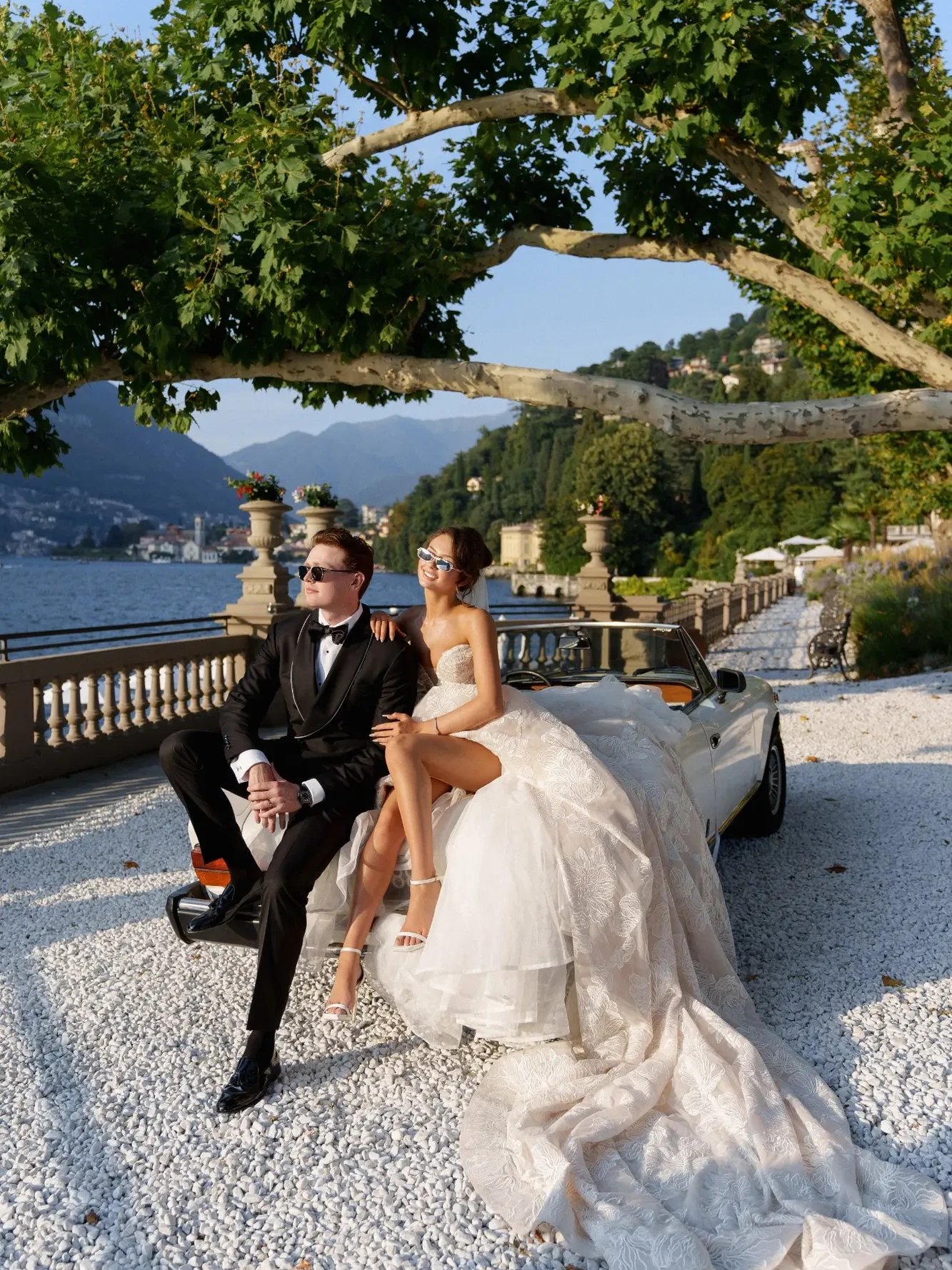 Rose and Hunter sitting on a vintage convertible beside Lake Como