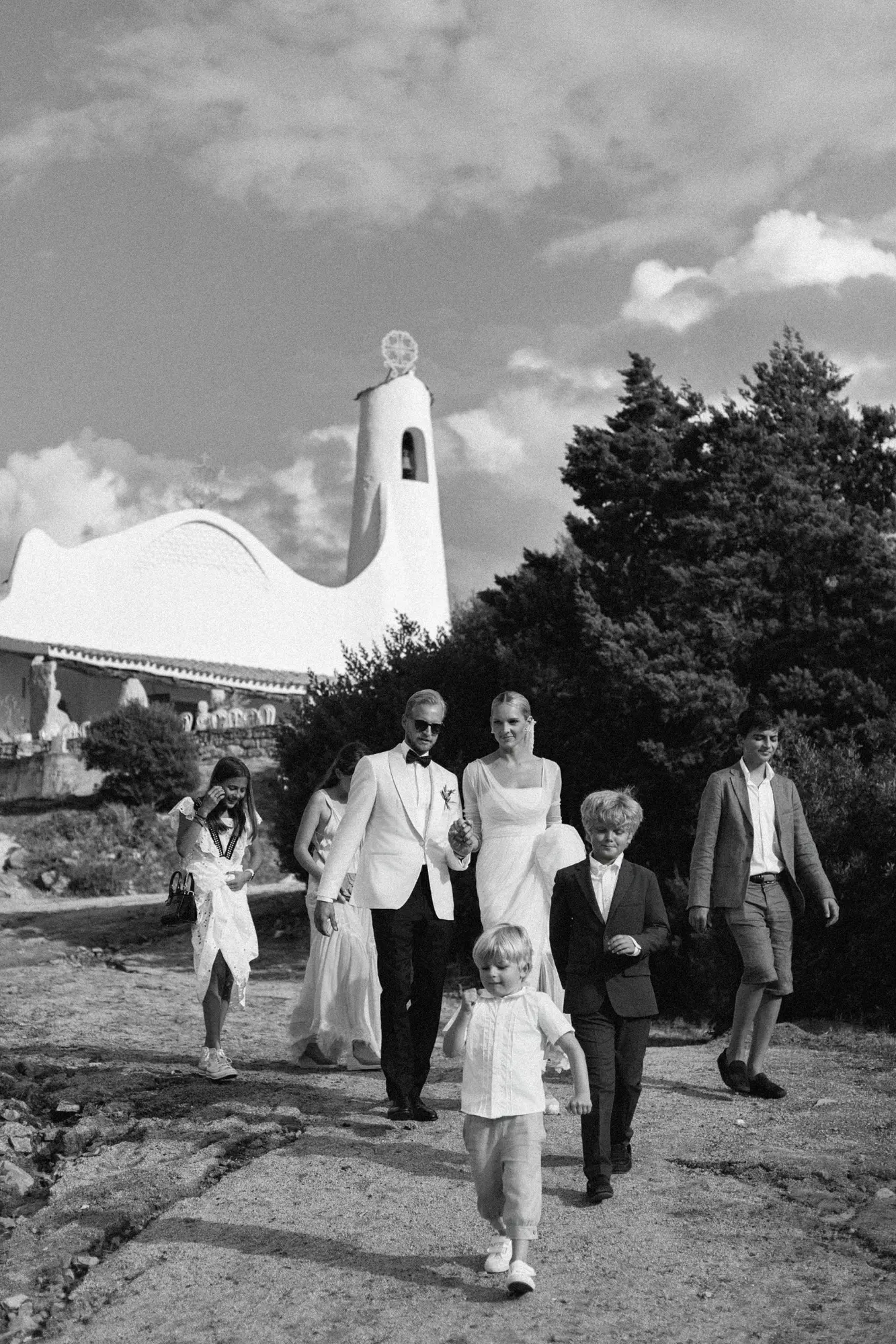 Laura and Leo walking with their family after their wedding ceremony in Sardinia